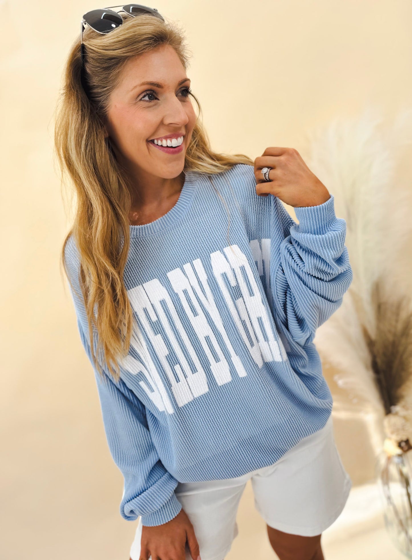 Person wearing a blue 'Saved by Grace' sweater, standing