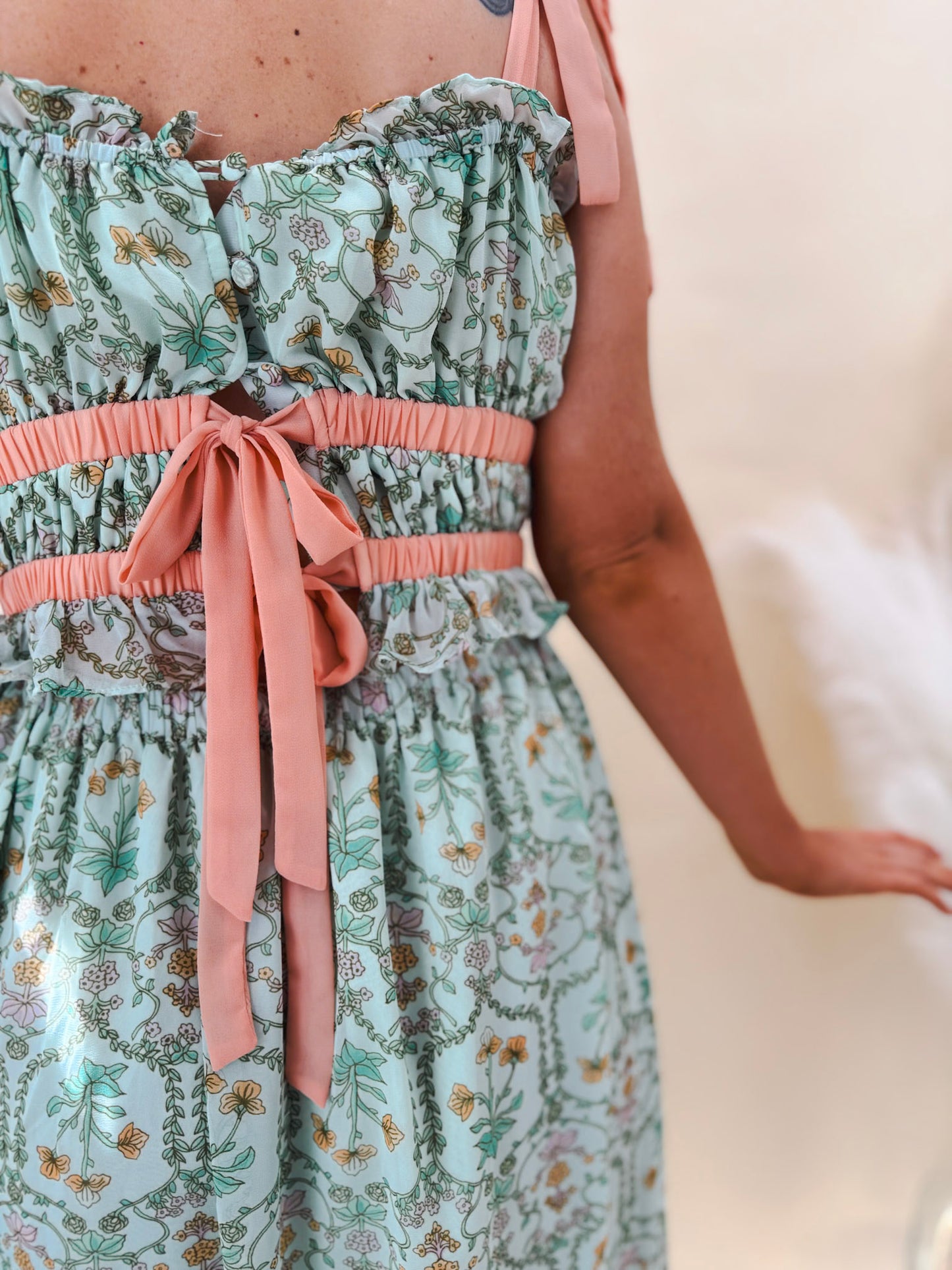 Close up back view of sage green midi dress with coral ribbon ties