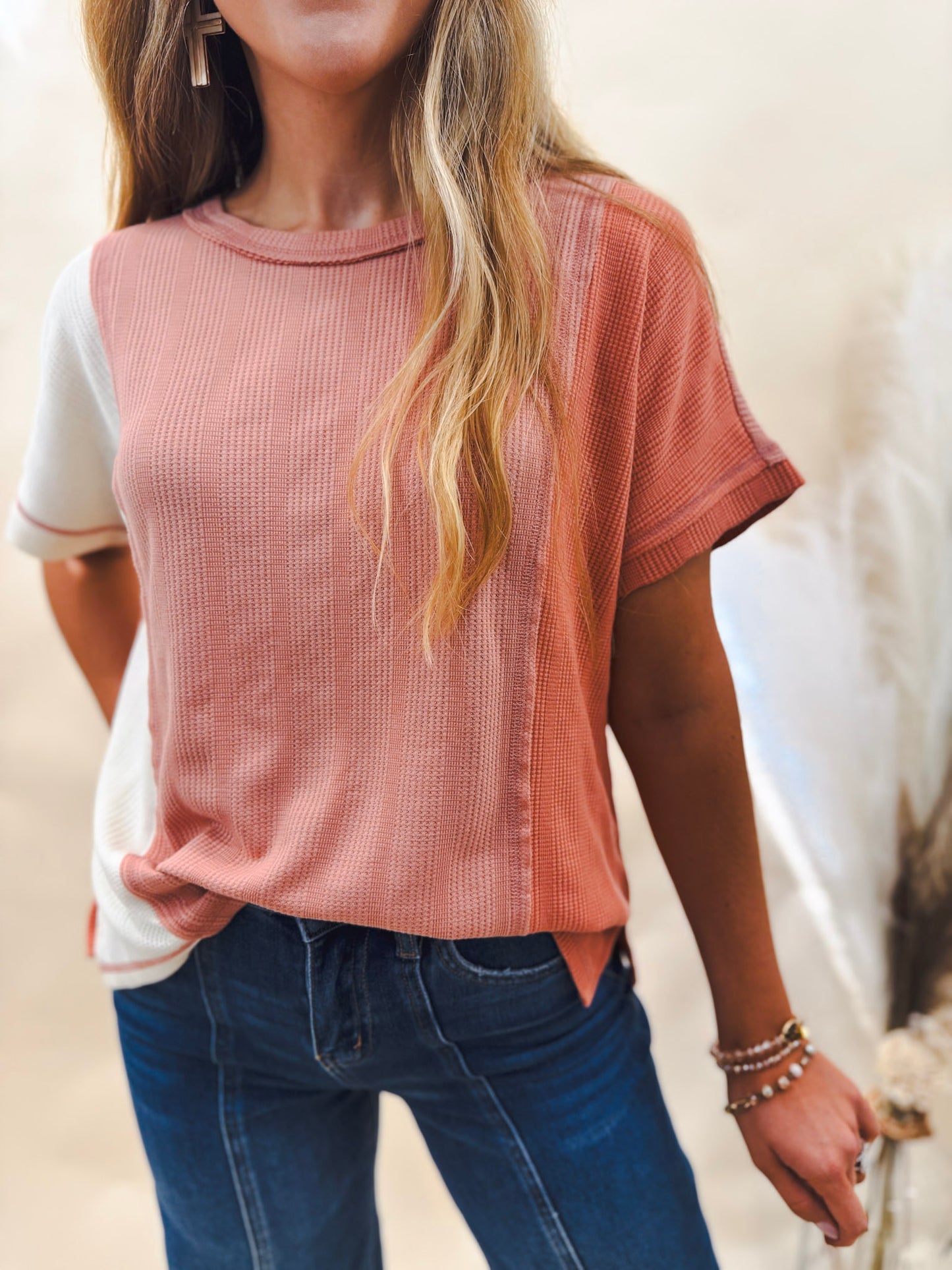 white, coral and salmon color blocked top worn with dark denim by a model