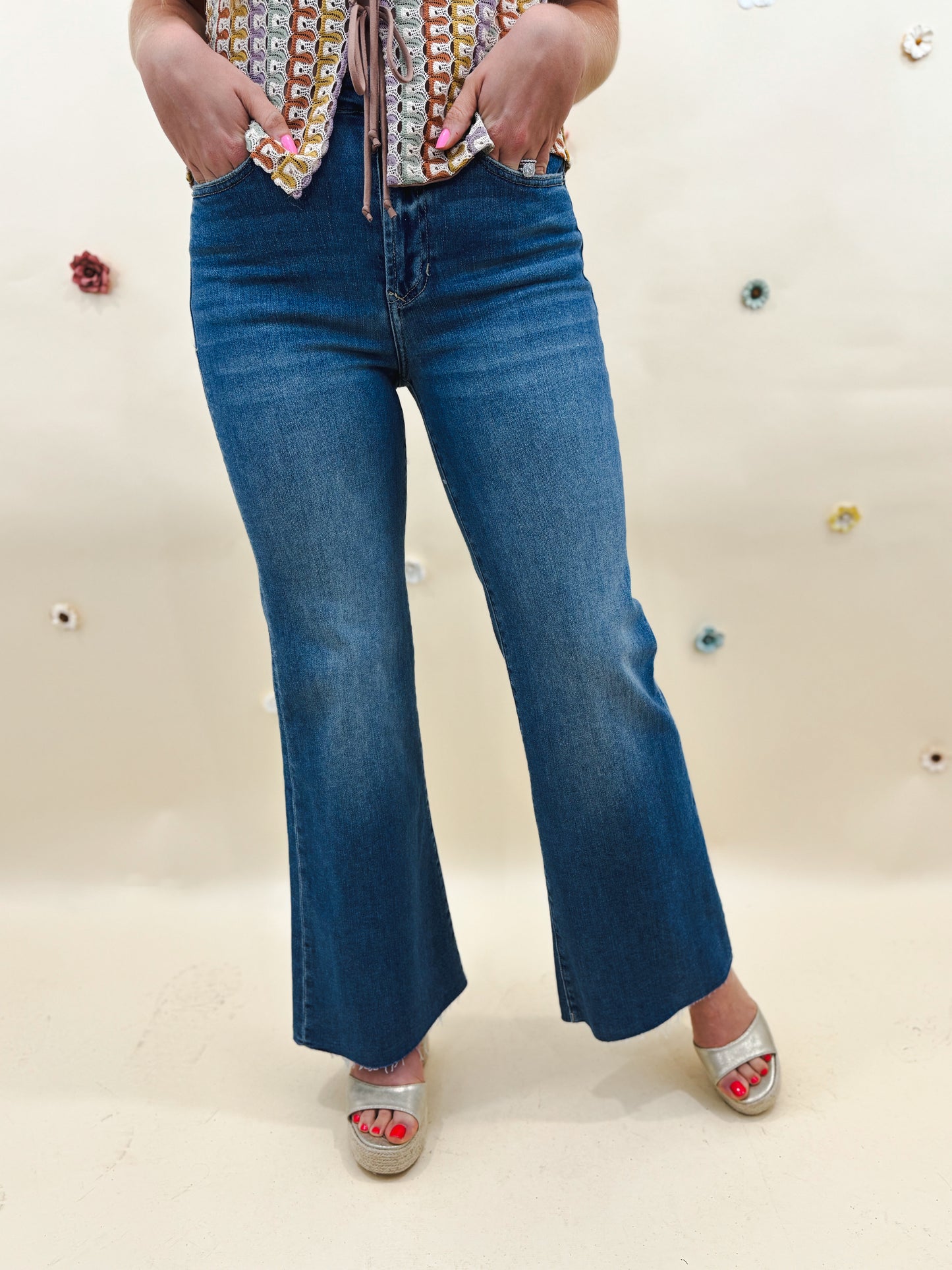 bottom half of model that is wearing medium wash denim in front of a tan background with multi colored flowers