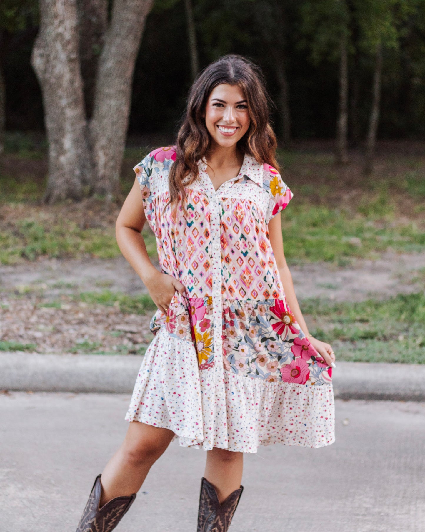 Woman wearing a boho patchwork mini dress with cap sleeves, button-down front, and pockets, styled with cowboy boots for a chic western-inspired look.