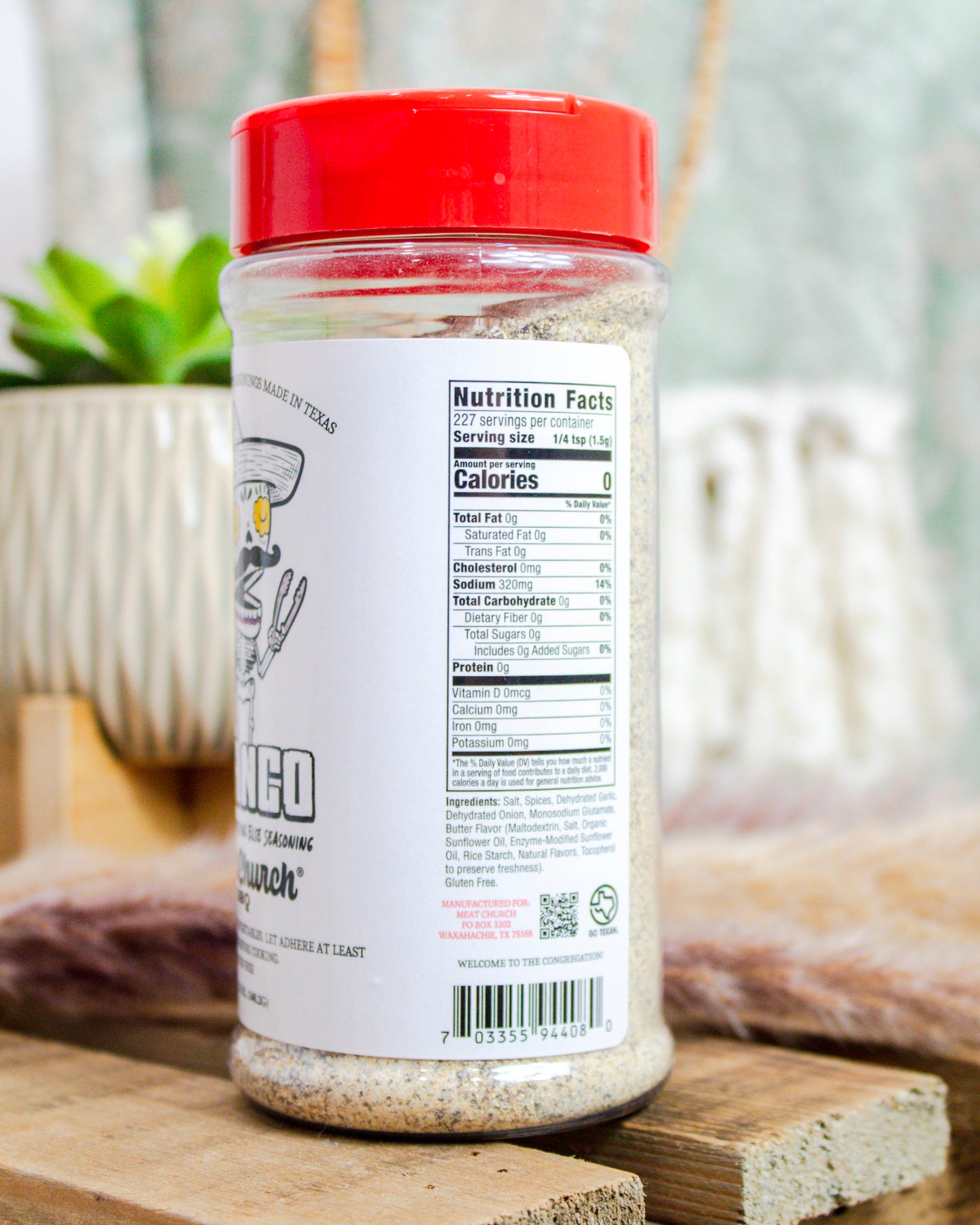 Container of a seasoning with a red lid on a wooden surface, blurred background