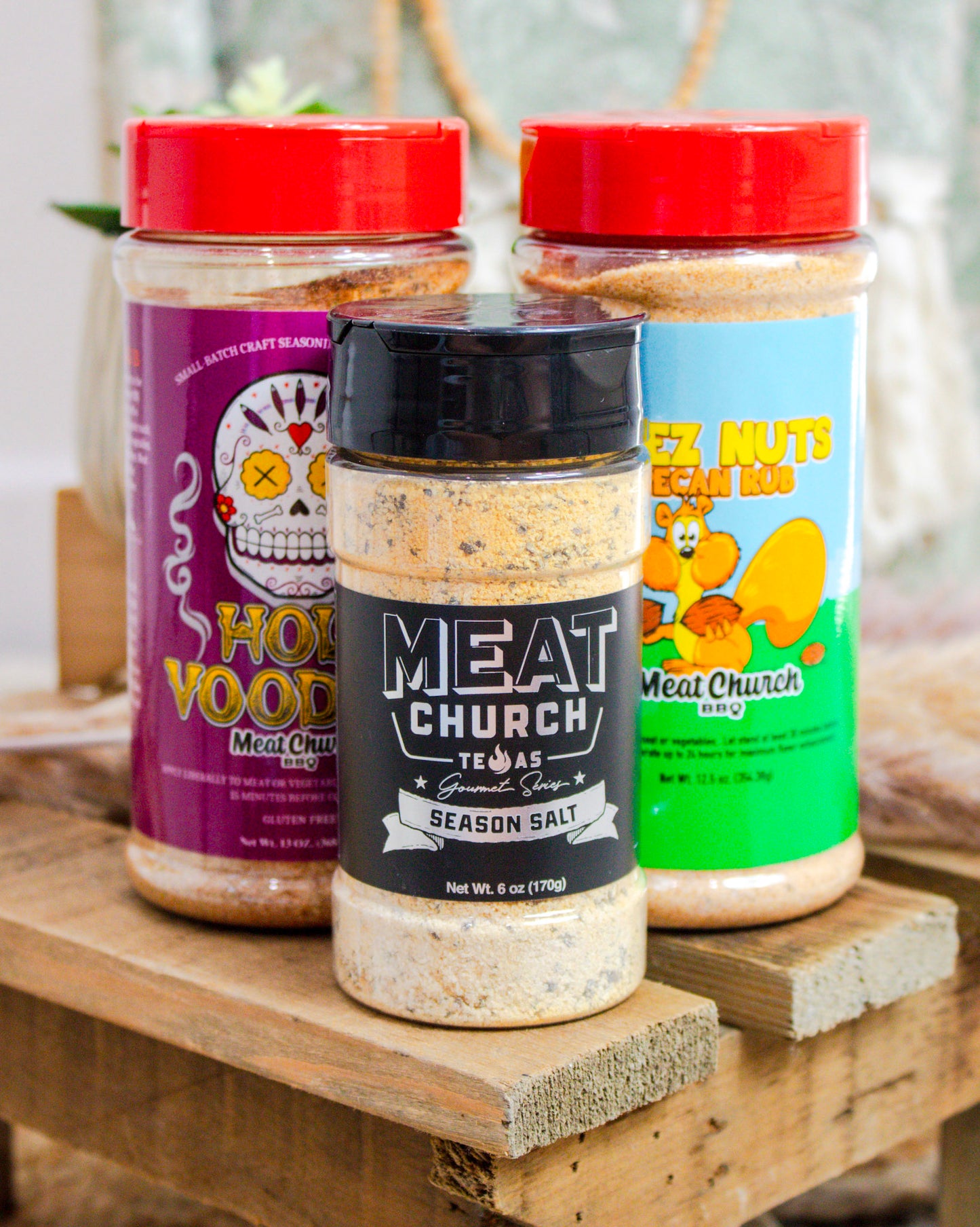 Three seasoning jars from Meat Church on a wooden surface