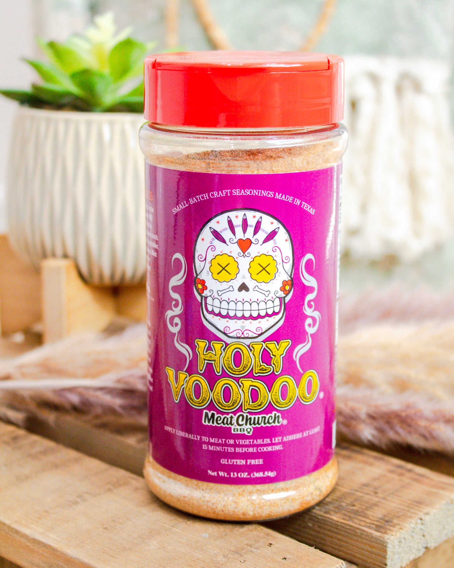 Jar of 'Holy Voodoo' meat tenderizer on a wooden surface with a blurred background
