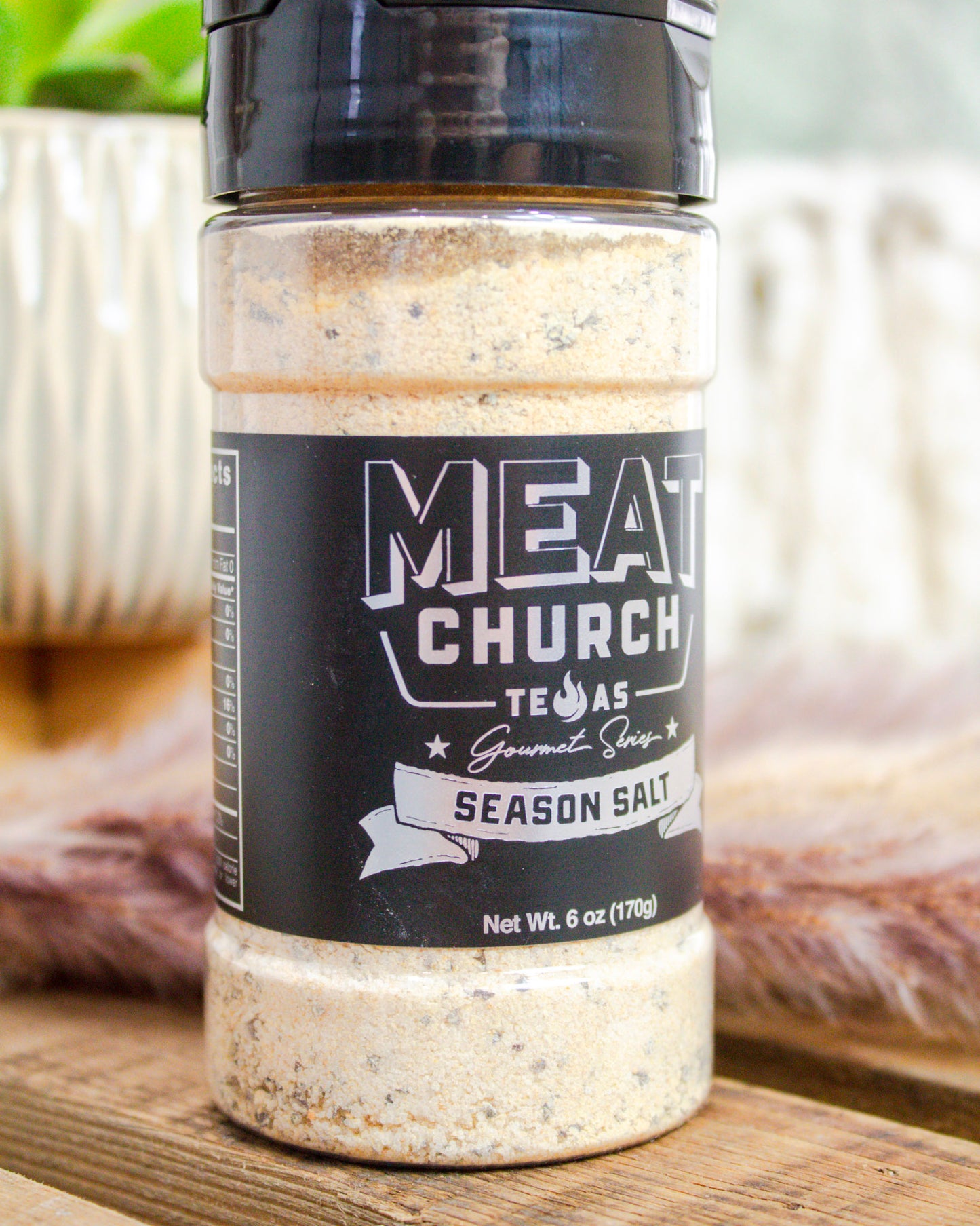 Bottle of Meat Church seasoning salt on a wooden surface with blurred background