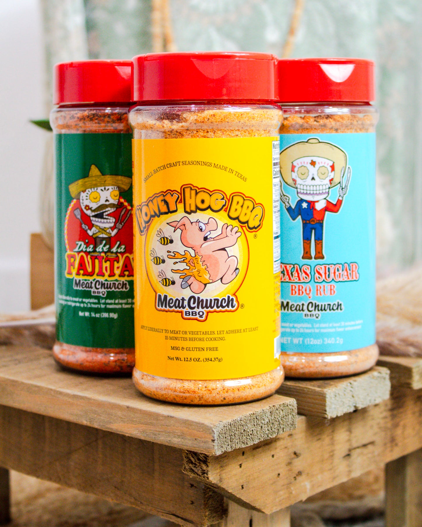 Three jars of 'Meat Church' BBQ products on a wooden surface with a blurred background.