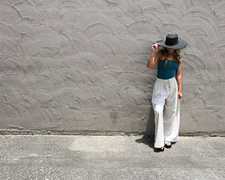 Teal strapless tube top paired with ivory wide-leg linen pants and a black wide-brim hat for effortless boho chic summer style and vacation-ready fashion.