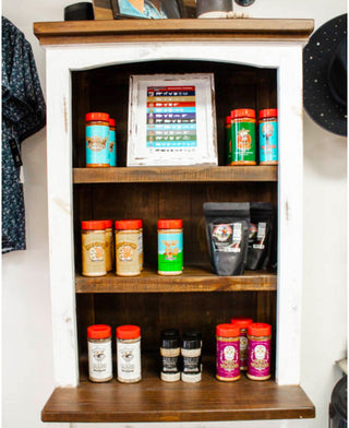 Rustic wooden shelf display featuring assorted Meat Church seasonings and rubs, including Holy Voodoo, Honey Hog, and Texas Chili, at Makenzie Layne Boutique