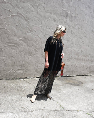 Black lace maxi dress with sheer lace hem styled with western boots and sunglasses for edgy boutique fashion, concert outfits, and modern boho style.