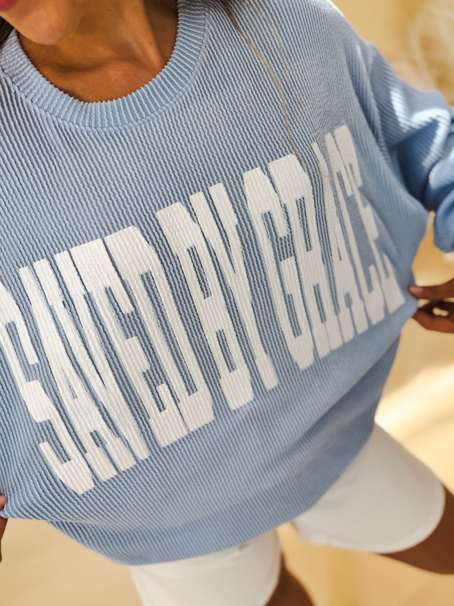 Close-up of the text 'Saved by Grace' on a blue crewneck sweater