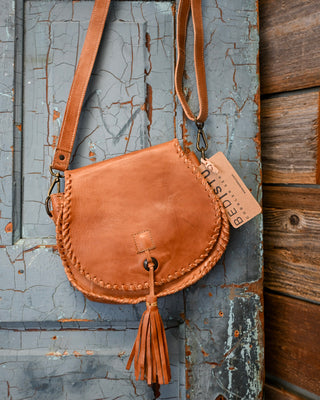 BED|STÜ tan leather crossbody bag with handwoven whipstitch detailing, tassel accent, and adjustable strap. Artisan boho handbag perfect for everyday wear.