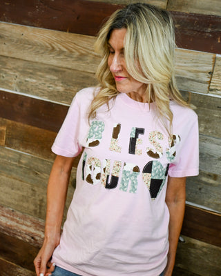 Women’s pink “Bless Your Heart” graphic t-shirt with mixed print lettering, soft casual fit, styled with denim jeans, trendy southern boutique style outfit