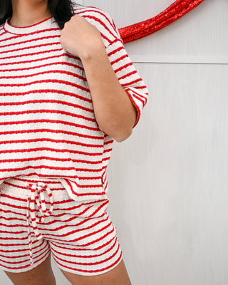 Person wearing a red and white striped outfit against a plain background