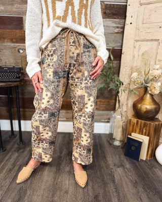 Women's brown and cream paisley patchwork pants with a drawstring waist, relaxed straight-leg fit, and vintage-inspired print, styled with an ivory TEXAS sweater at MaKenzie Layne Boutique.