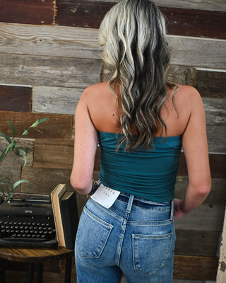 Back view of a teal strapless tube top styled with light wash high-rise jeans for trendy boutique fashion, casual summer outfits, and everyday style.