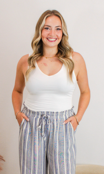 Woman wearing a white fitted tank top paired with high-waisted, blue and white striped wide-leg drawstring pants, styled for a casual and comfortable summer look.