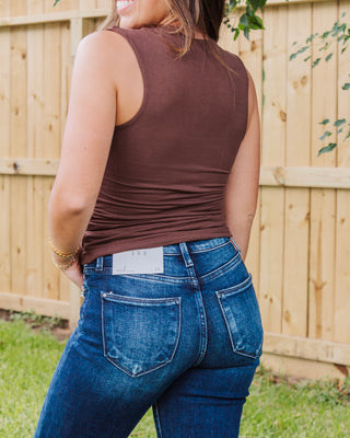 Back view of woman wearing high-rise dark wash skinny jeans with slight fading, paired with a sleeveless brown top for a flattering casual look.