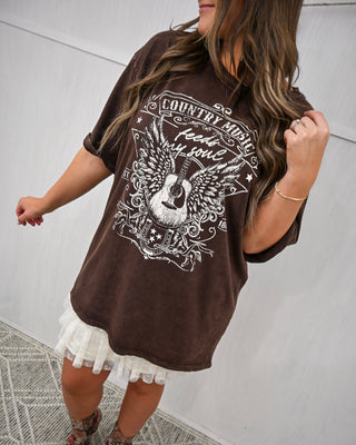 Woman wearing a brown oversized t-shirt with graphic design against a white background