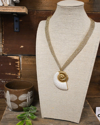 Gold layered chain necklace featuring a white nautilus shell pendant with gold spiral detailing, a coastal-inspired statement accessory perfect for beachy boutique style.
