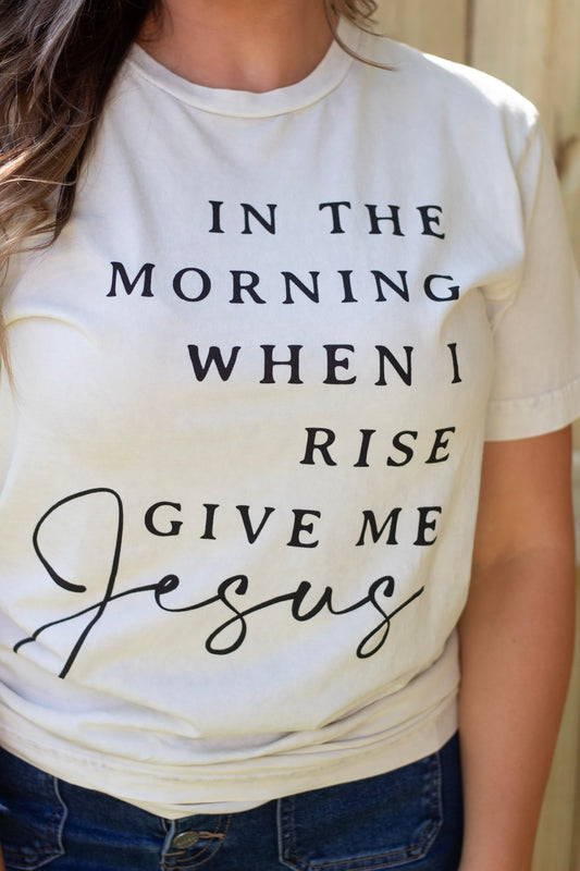 A close-up of a white Christian t-shirt with the inspirational quote, "In the morning when I rise give me Jesus."