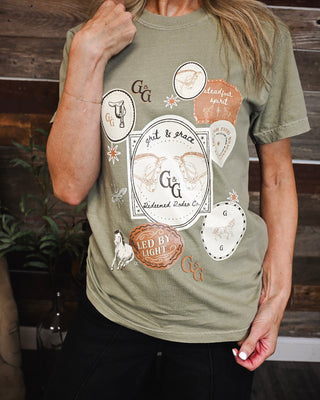 Women's sage green western graphic tee featuring horses, rodeo-inspired artwork, and faith-based details in neutral tones for a trendy casual boutique look.