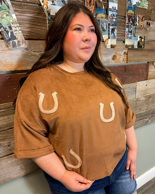 Plus size brown suede top with horseshoe applique details, relaxed fit, and short sleeves styled with denim shorts