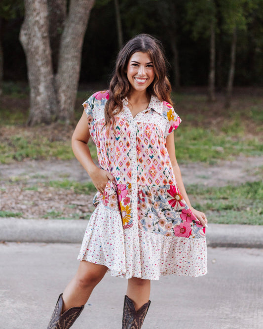 Woman wearing a boho patchwork mini dress with cap sleeves, button-down front, and pockets, styled with cowboy boots for a chic western-inspired look.