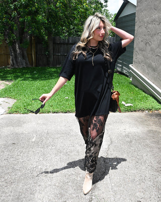 Black lace maxi dress with sheer floral lace hem styled with western boots and layered jewelry for trendy boutique fashion, concert outfits, and edgy boho style.
