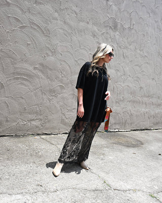 Black lace maxi dress with sheer lace hem styled with western boots and sunglasses for edgy boutique fashion, concert outfits, and modern boho style.