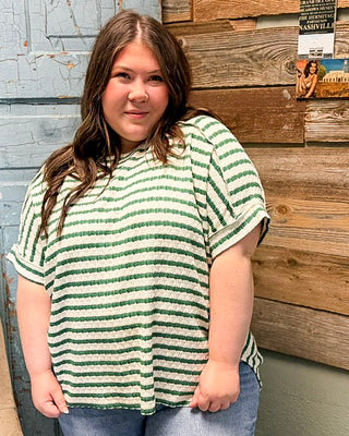 Plus size green and white striped textured top with relaxed fit and short sleeves, styled with denim jeans
