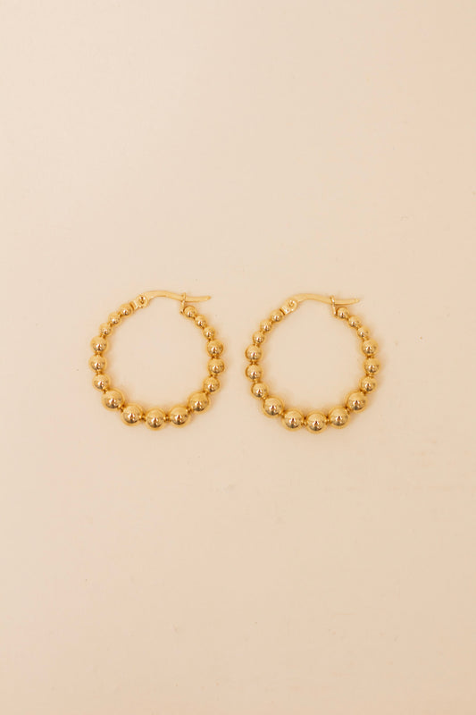 Pair of gold beaded hoop earrings featuring polished metallic round beads and latch-back closures, displayed on a neutral background. Classic and versatile gold hoops for everyday or dressy wear.