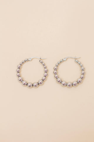 Pair of silver beaded hoop earrings featuring polished metallic round beads and a latch-back closure. Lightweight, trendy jewelry for everyday wear or special occasions.