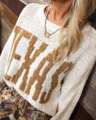 Close-up of a two-tone silver chain necklace with gold horseshoe clasp pendant, styled with a cream Texas graphic knit sweater for a trendy western boutique look.