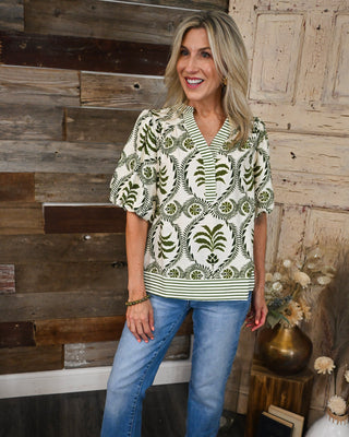 Ivory and olive green botanical print blouse with striped V-neck trim and puff sleeves, styled with light wash jeans for an elevated fall outfit.