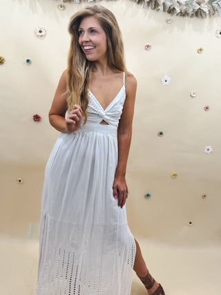 Woman wearing a white eyelet twist-front maxi dress with spaghetti straps and cutout detail, perfect for summer events or bridal showers.