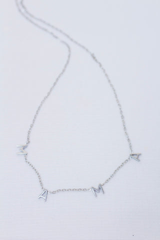 Delicate silver chain necklace featuring individual letter charms that spell 'MAMA'. Minimalist and meaningful jewelry piece, perfect for Mother's Day or everyday wear.