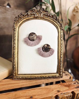 Women's boho statement earrings featuring marbled brown and black round studs with dusty mauve fan-shaped fringe tassels for a chic western-inspired accessory.