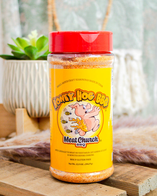 Meat Church Honey Hog BBQ seasoning rub, 12.5 oz bottle with bright yellow label and cartoon pig—sweet Texas BBQ flavor at Makenzie Layne Boutique