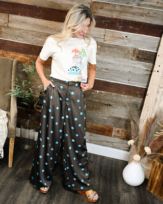 Women's brown satin wide leg pants with blue polka dots, styled with an ivory graphic tee for a playful, trendy boutique outfit.