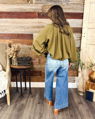 Women’s olive green balloon sleeve jacket with a relaxed cropped fit and gathered back, styled with medium wash wide leg jeans for an elevated fall look.