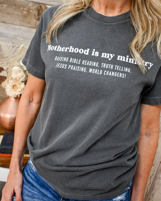 Women’s charcoal gray graphic t-shirt with “Motherhood is my ministry” quote, faith-based tee, soft casual top styled with denim, Christian boutique apparel.