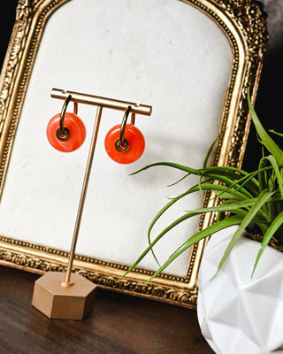 Orange statement hoop earrings with bold circular resin drops and gold-tone accents, adding a playful pop of color to any boutique outfit.