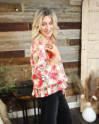 Women's floral ruffle jacket featuring a cream base with pink, coral and olive floral print, statement sleeves and a feminine tiered ruffle hem.