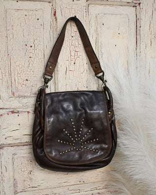 Distressed brown leather shoulder bag with studded starburst detail, flap closure, and vintage-inspired hardware. Western boho handbag perfect for everyday style.