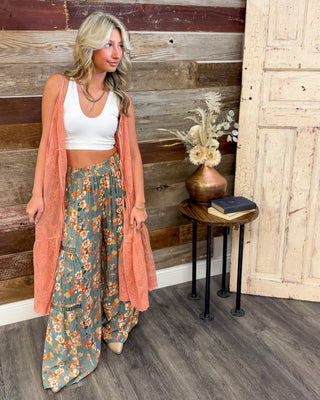 Boho outfit with sage green floral wide leg pants, white crop tank, and peach lace duster, styled with neutral heels