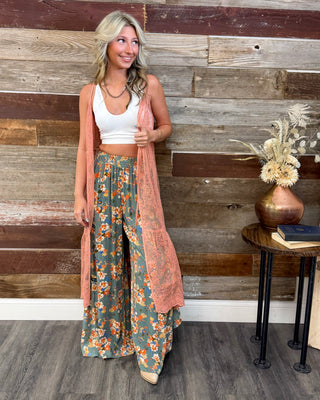 Boho outfit with sage green floral wide leg pants, white crop tank, and peach lace duster, styled with neutral pointed toe heels