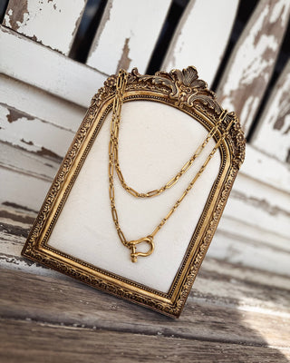 Gold layered paperclip chain necklace featuring two delicate strands and a statement shackle-shaped clasp pendant, a trendy western-inspired jewelry piece from MaKenzie Layne Boutique.