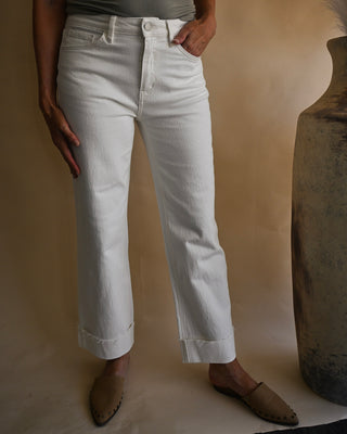 White cropped straight leg jeans with a high-rise fit, cuffed raw hem, and classic five-pocket styling. Women's versatile white denim pants styled for a chic boutique outfit.