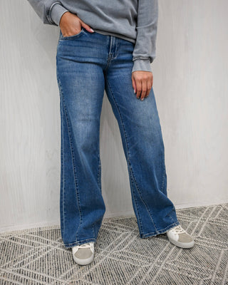 Person wearing blue jeans and a gray sweatshirt against a plain background