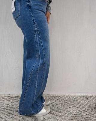 Person wearing blue jeans standing against a plain background